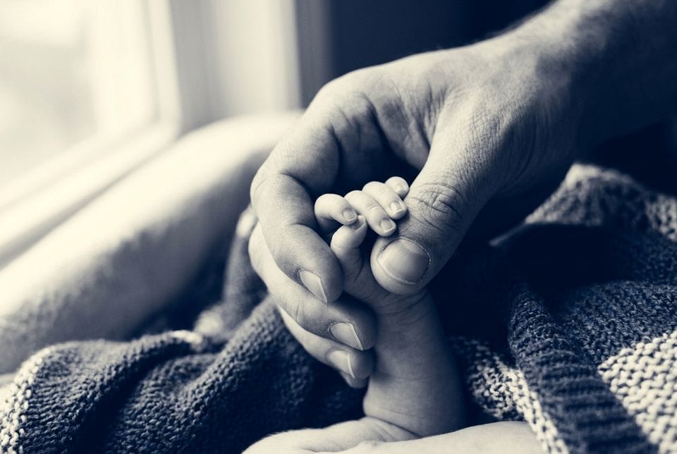 A father holding a newborn baby's hand
